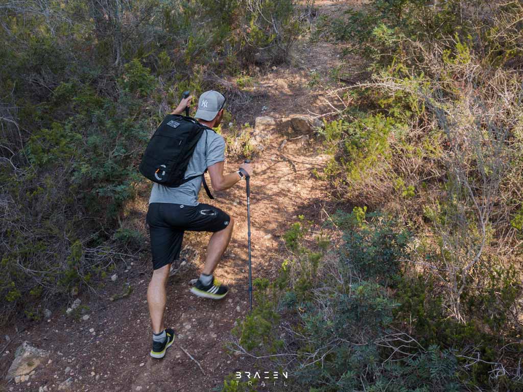 young hiker ascending hill with trekking poles